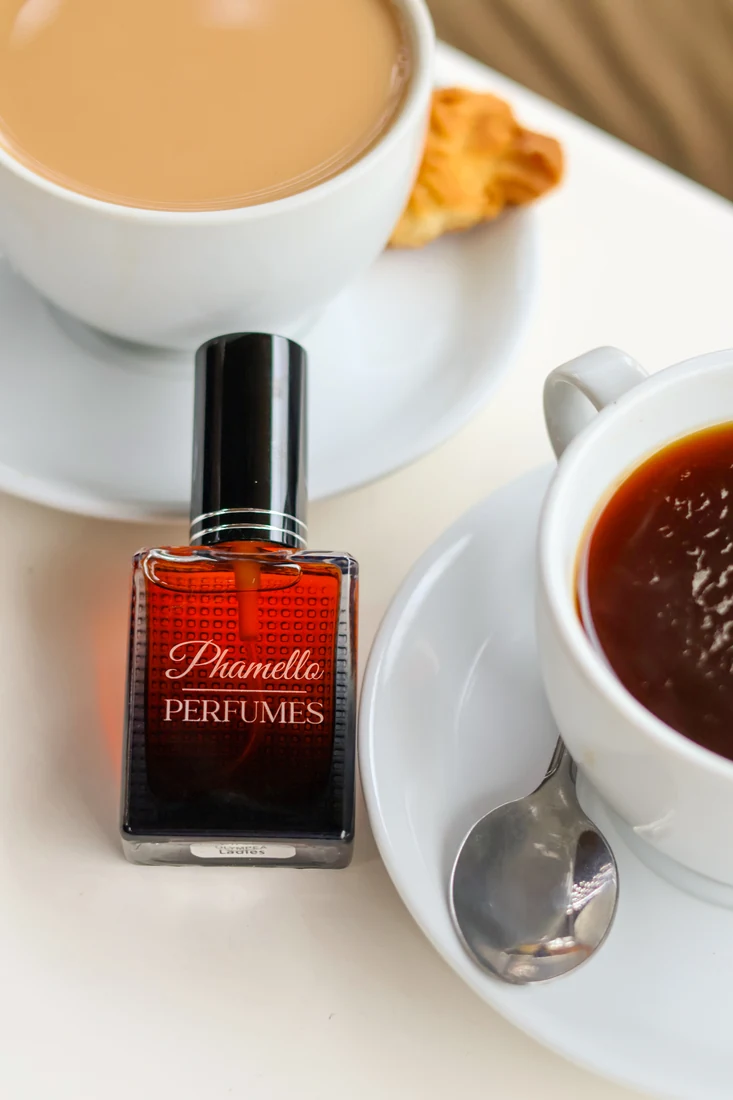 Perfume bottle on a table beside coffee cups